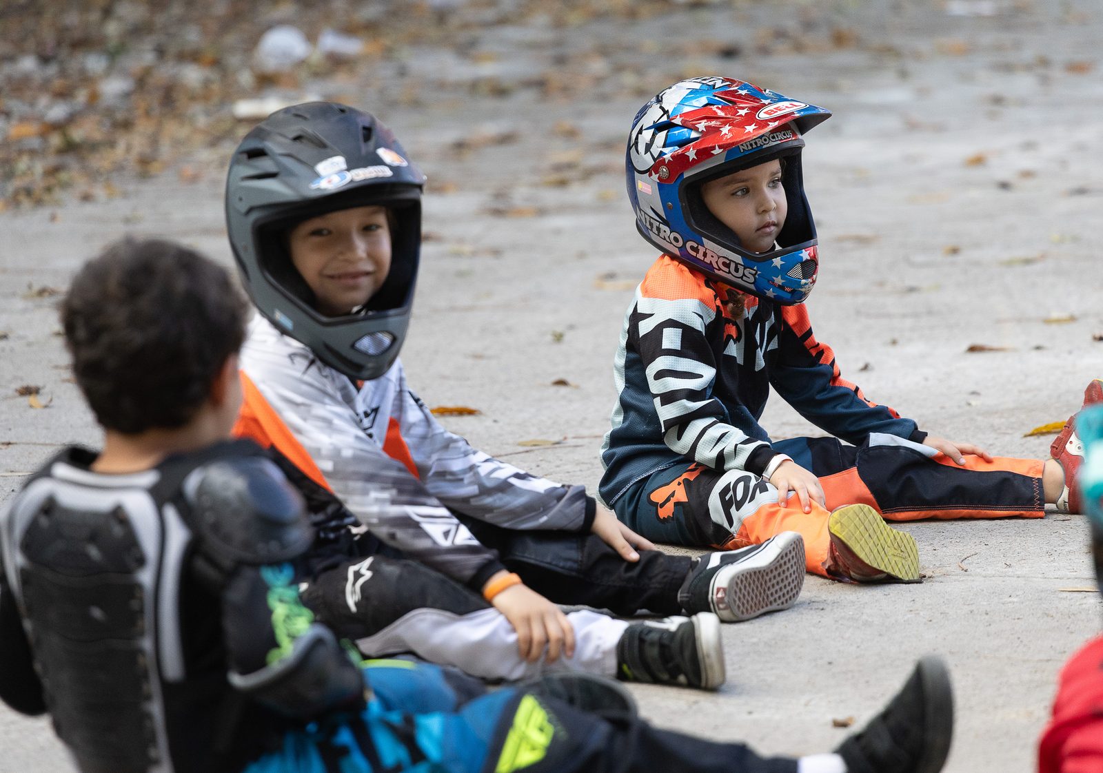 Niños con casco sentados durante el calentamiento de la clase